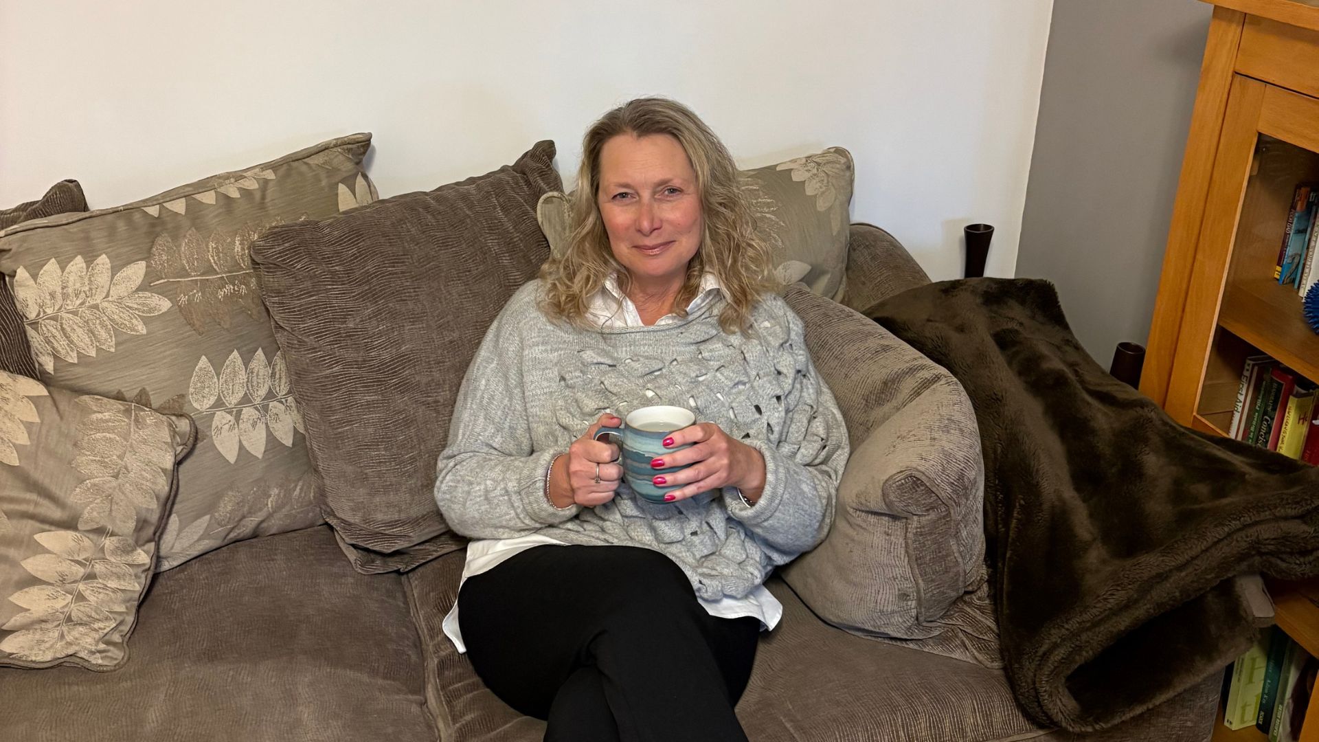 Karen Baker, the hypnotherapist, Knutsford Cheshire, on her sofa drinking a hot drink, showing how approachable she is.