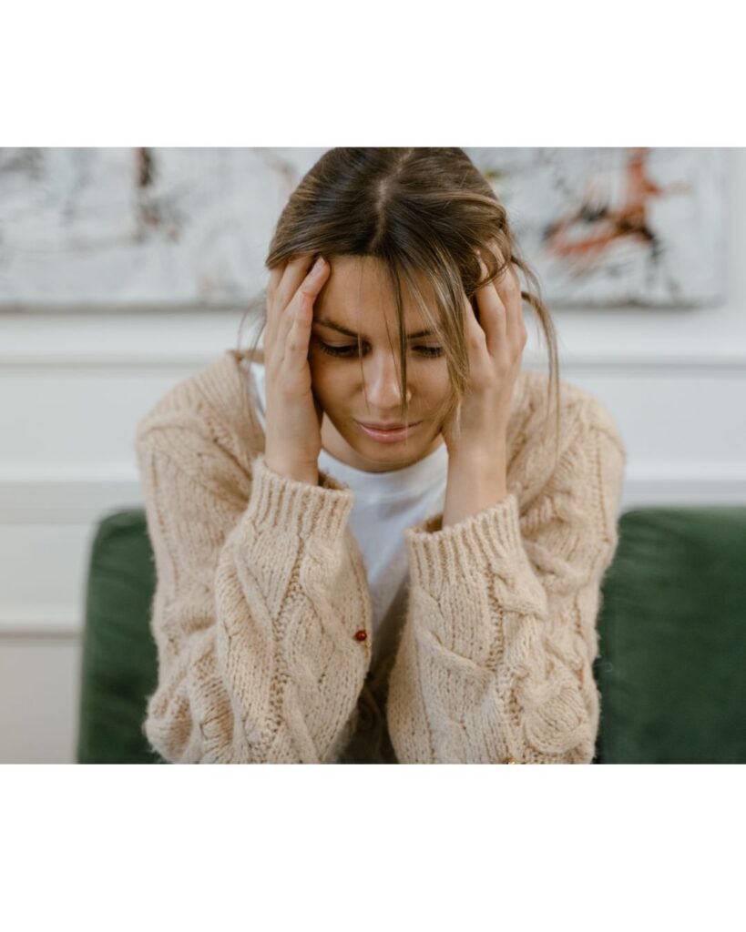 Picture of a woman with her head in her hands, looking stressed. Showing that hypnotherapy can help with anxiety and stress.