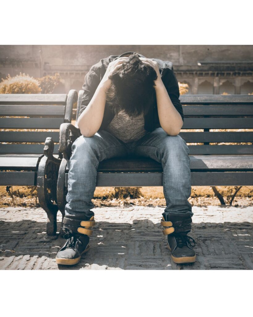 Picture of a man with his head in his hands, looking stressed. Showing that hypnotherapy can help with anxiety and stress.