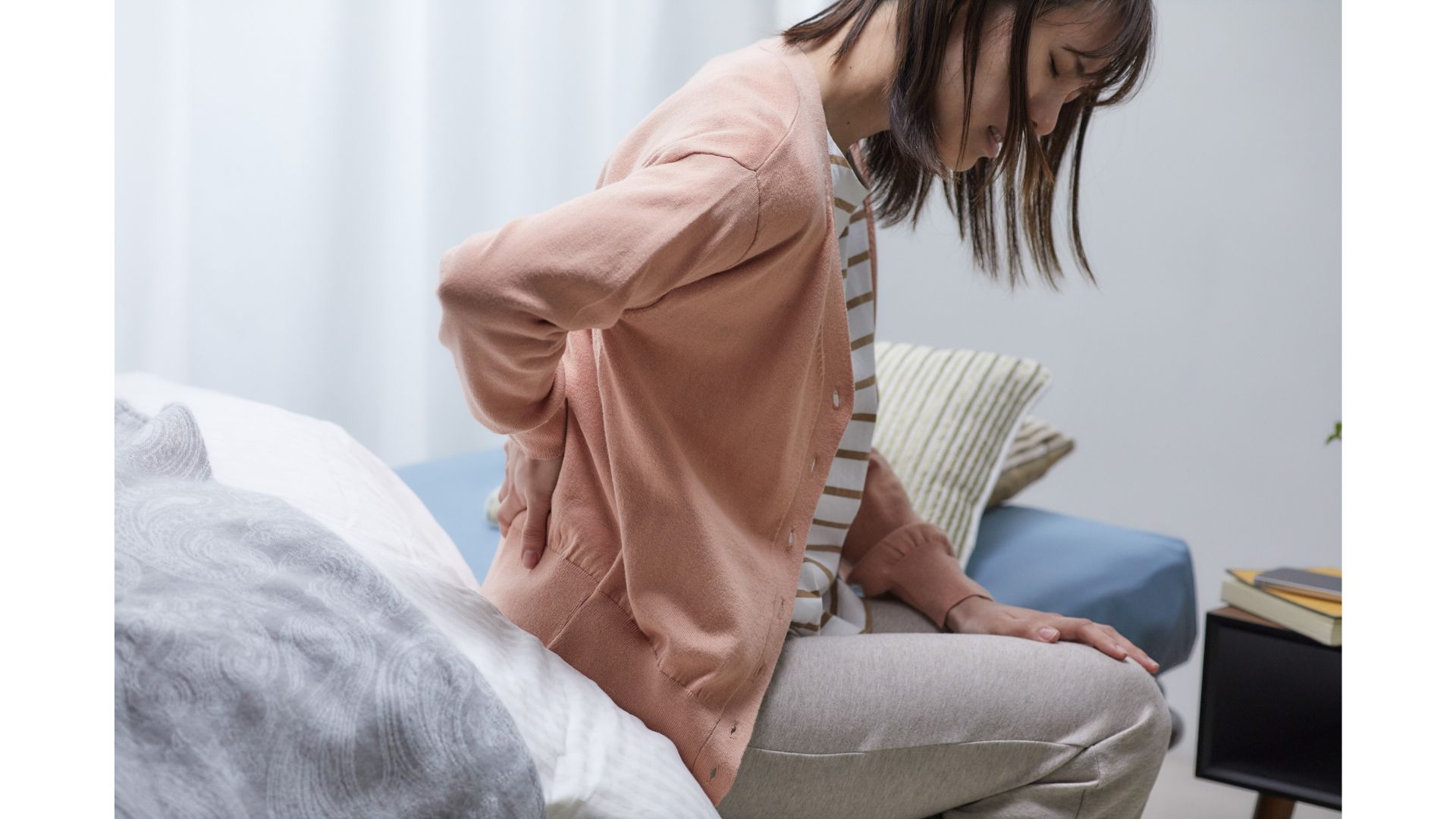 A picture of a woman rubbing her back, showing that hypnotherapy can help you if you're suffering from back pain.