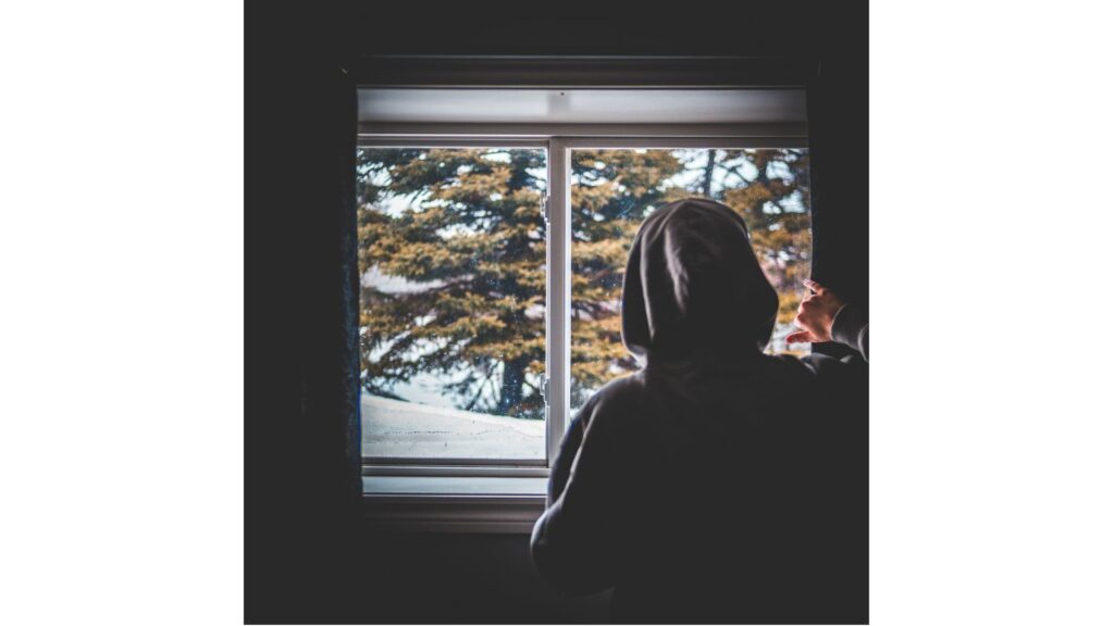 Picture of a woman looking out of the window, showing how hypnotherapy may help you if you suffer from agoraphobia.