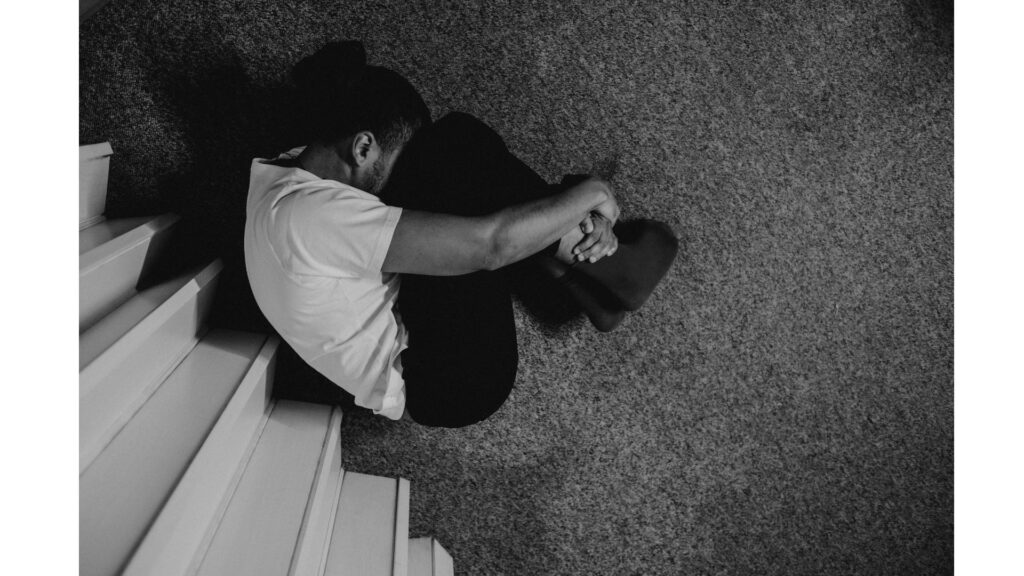 Picture of a man curled up on the floor, showing how hypnotherapy could help you overcome your fear of open spaces.